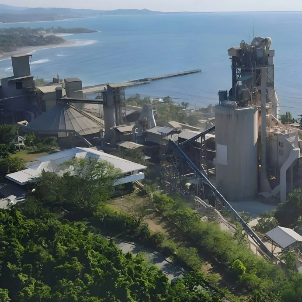 Aerial view of a coastal cement plant with industrial buildings and conveyor systems